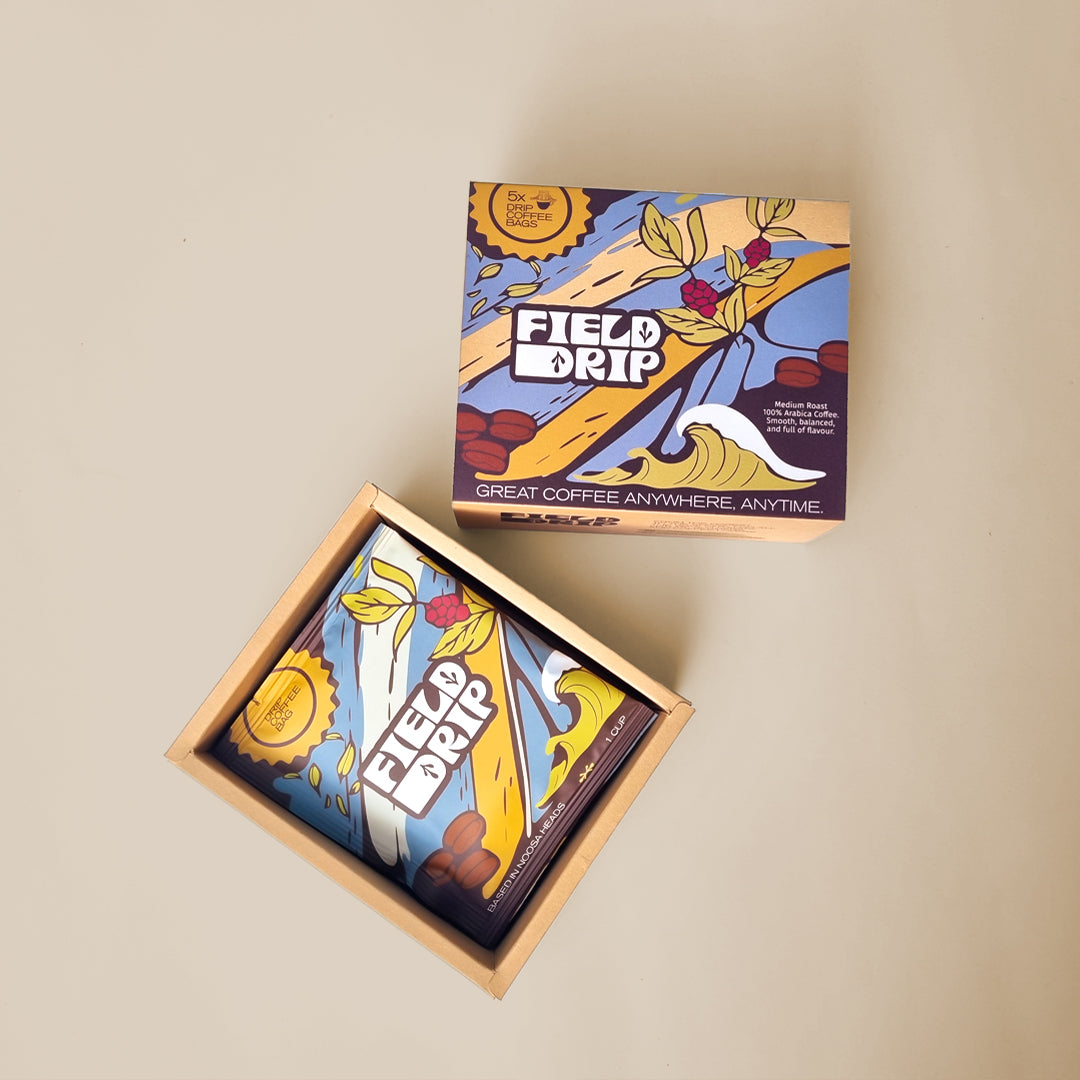 A box of Field Drip coffee with its lid open, showing five individually packaged drip coffee bags.