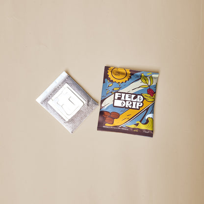 Field Drip single-serve drip coffee bag and filter sachet flat lay on beige background