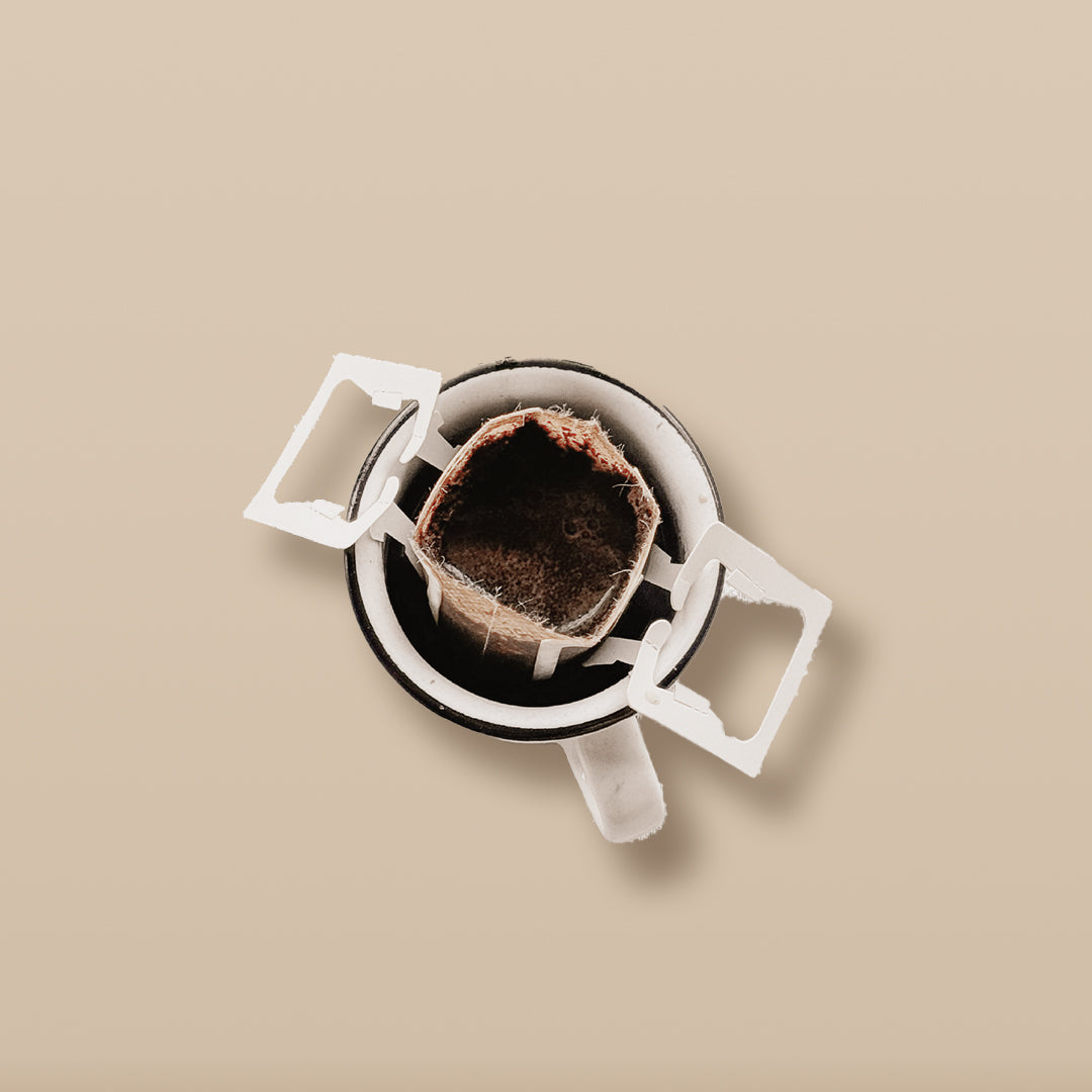 Field Drip single-serve drip coffee filter hooked on a cup, top-down, brewing step before pouring.